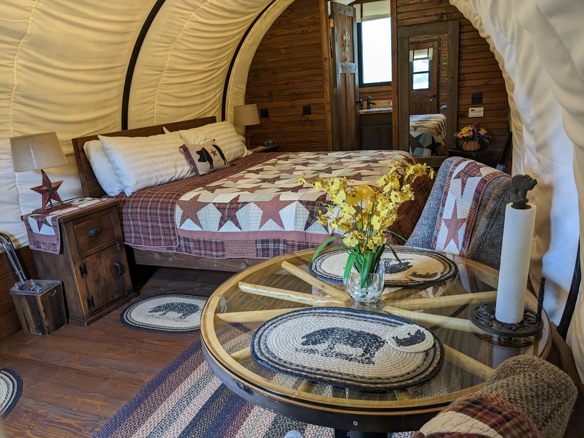 Inside a covered wagon: a quilted king bed and a wagon-wheel table