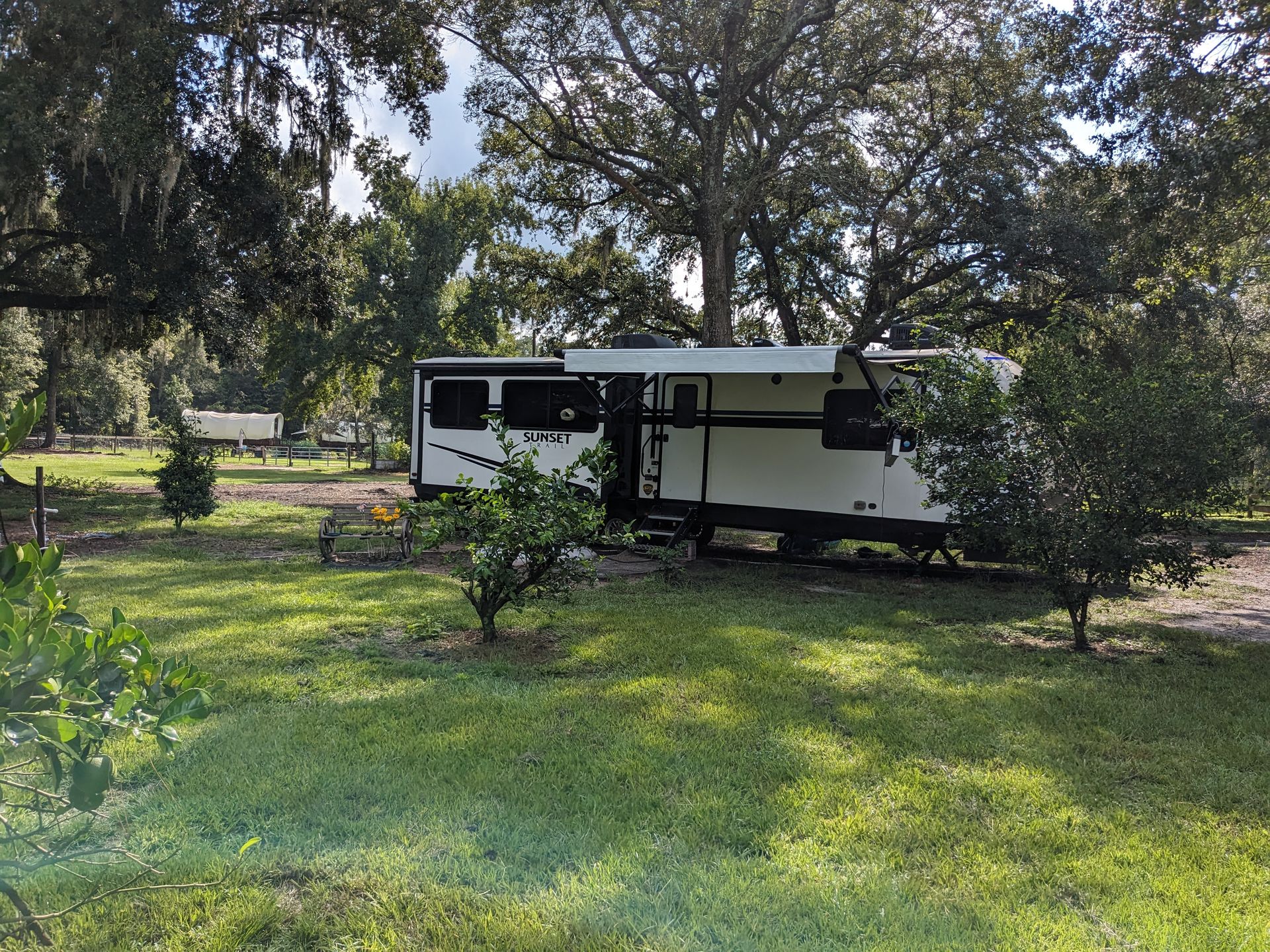 An RV parked under the live oaks on the green