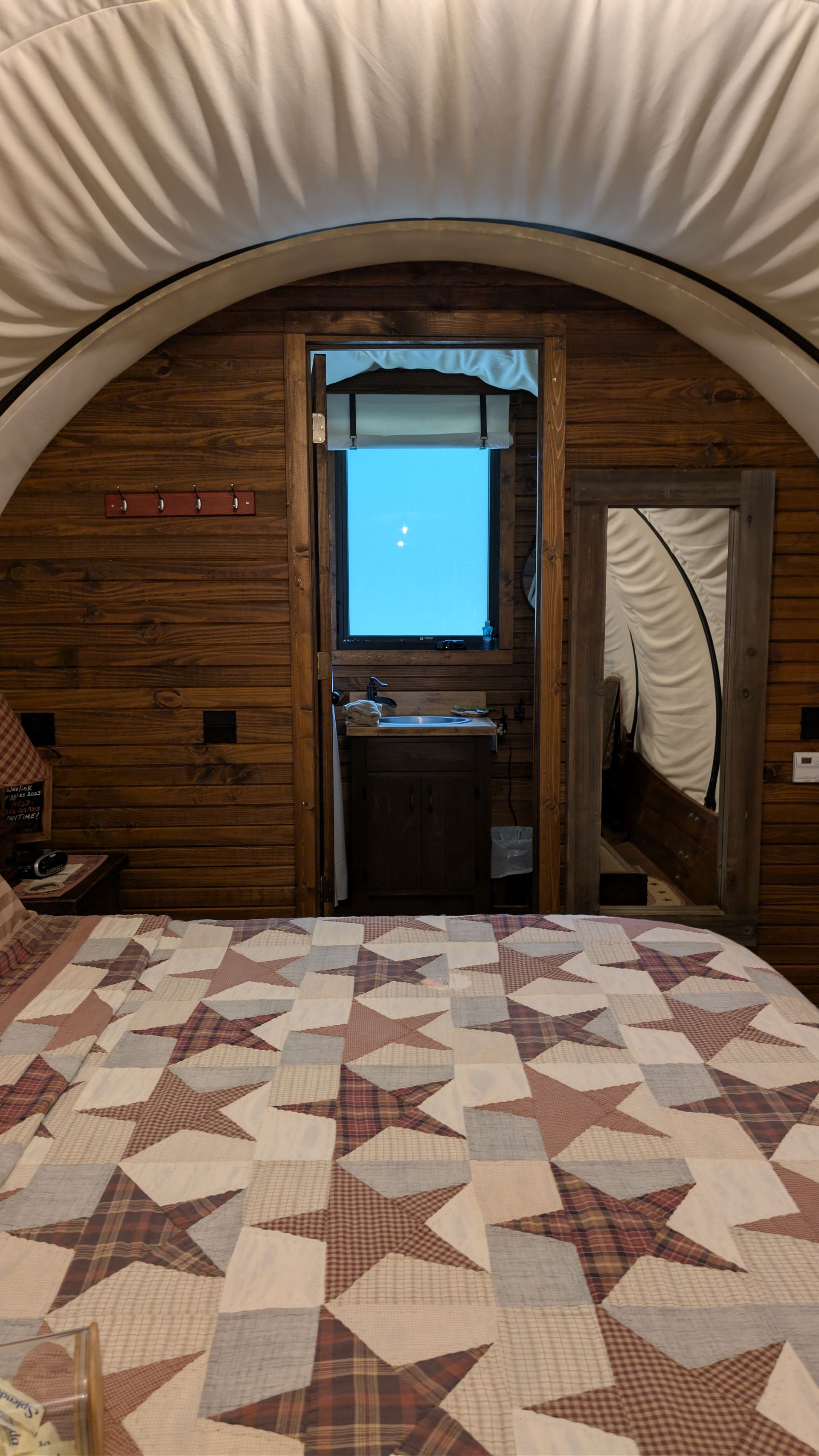 The arched interior of a wagon with a star quilt on the bed